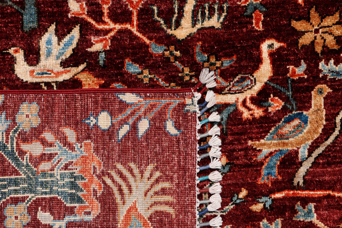 A hand-knotted wool rug with detailed peacock and bird design.