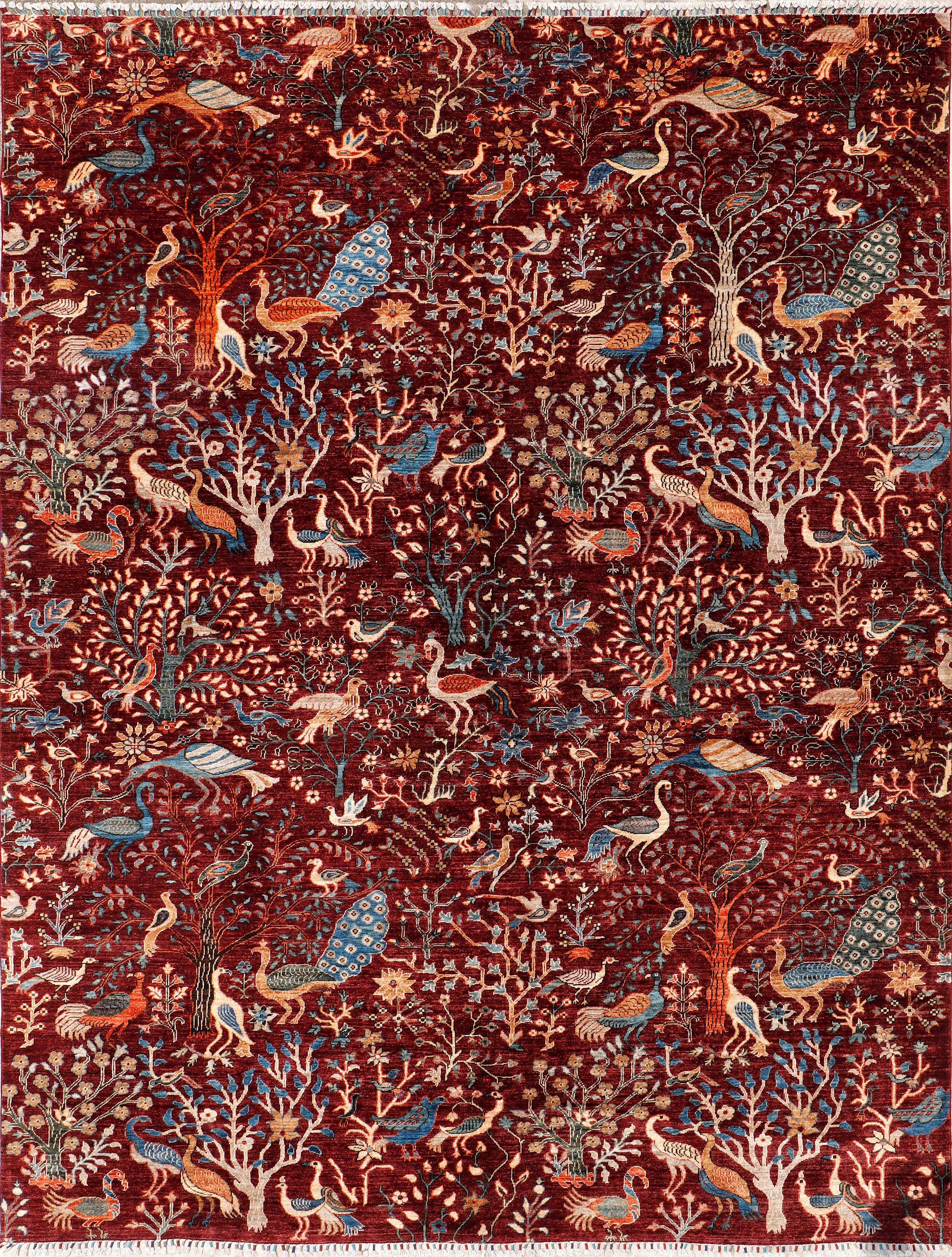 A hand-knotted wool rug with detailed peacock and bird design.
